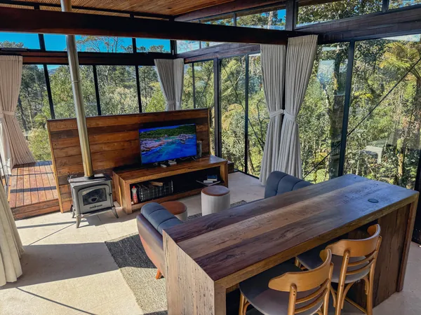 Sala da Cabana Cristal com lareira, mesa e paredes de vidro