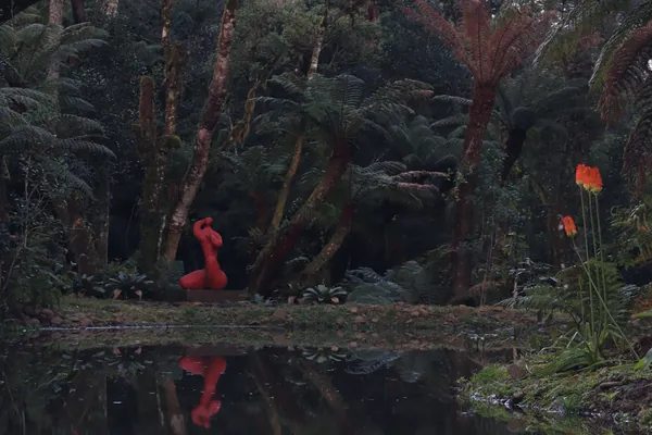 O lago do jardim com uma escultura vermelha refletida na água